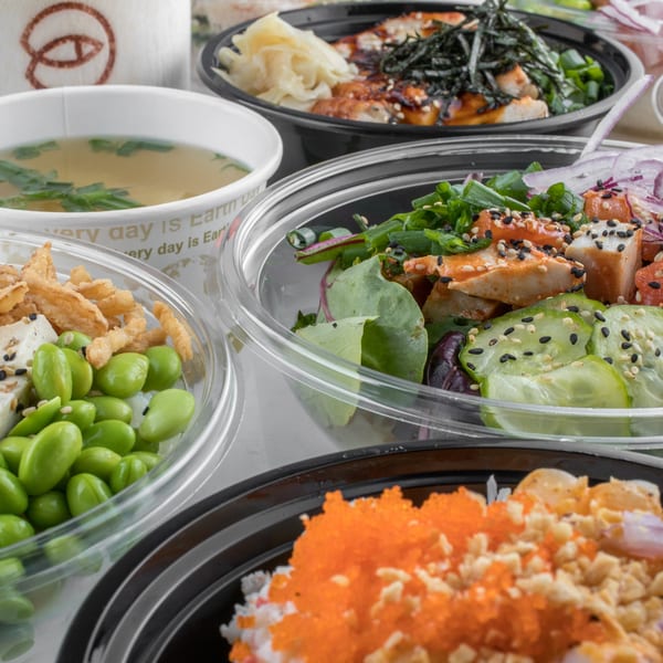 Assortment of Hi Poke bowls and miso soup, featuring fresh ingredients like edamame, fish, and vegetables.