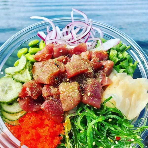 Close-up of a Hi Poke bowl with tuna, red onions, edamame, cucumbers, roe, and seaweed.